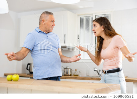 Domestic quarrel between elderly father and adult daughter in kitchen Domestic quarrel between elderly father and adult daughter in kitchen 109906581