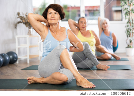 Senior lady performs cow head pose, Gomukhasana 109906612