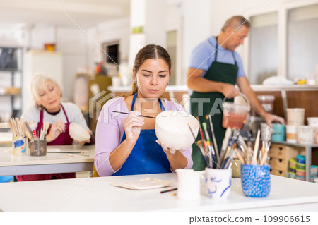 Woman learning to paint pottery at pottery class 109906615