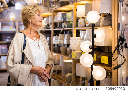 Mature woman choosing new lamp at shop 109906910