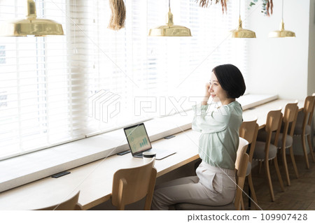 A woman stretches while working at a desk 109907428