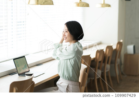 一位女士在辦公桌前工作時伸展身體 109907429