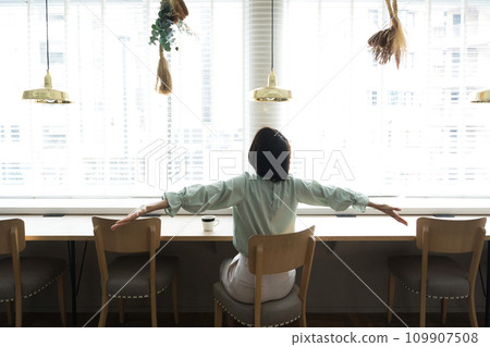 A woman sitting by the window and spreading her arms A woman sitting by the window and spreading her arms 109907508