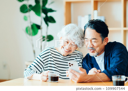 A senior couple looking at their smartphones together. 109907544