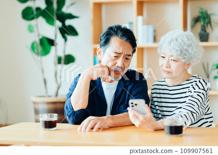 A senior couple looking at their smartphones together. 109907561