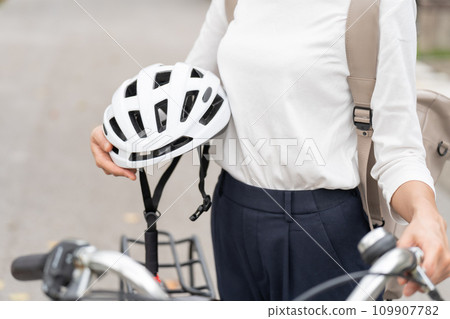 Young woman holding a helmet next to her mamachari, parts cut 109907782