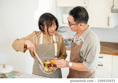 Happy adult Asian couples are cooking in the kitchen together, making a salad bowl. 109910933