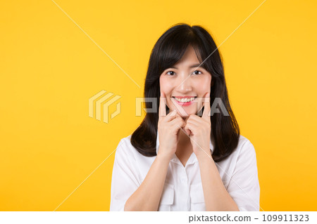 Young beautiful asian woman happy smile wearing white shirt and denim jean plants over yellow isolated background smiling confident showing and pointing with fingers teeth and mouth. Dental concept. 109911323