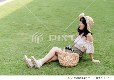 Portrait of asian young woman traveler with weaving hat and basket and a camera on green public park nature background. Journey trip lifestyle, world travel explorer or Asia summer tourism concept. Portrait of asian young woman traveler with weaving hat and basket and a camera on green public park nature background. Journey trip lifestyle, world travel explorer or Asia summer tourism concept. 109911462