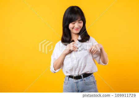 Captivating image of Asian young woman wearing white shirt and denim jeans, confidently holding cash from her shirt pocket. Fashion meets financial empowerment. Perfect for finance and fashion themes. Captivating image of Asian young woman wearing white shirt and denim jeans, confidently holding cash from her shirt pocket. Fashion meets financial empowerment. Perfect for finance and fashion themes. 109911729
