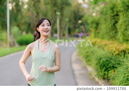 Fit Asian young woman jogging in park smiling happy running and enjoying a healthy outdoor lifestyle. Female jogger. Fitness runner girl in public park. healthy lifestyle and wellness being concept Fit Asian young woman jogging in park smiling happy running and enjoying a healthy outdoor lifestyle. Female jogger. Fitness runner girl in public park. healthy lifestyle and wellness being concept 109911788