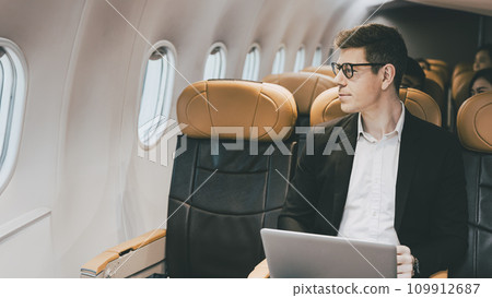 Businessman traveling by plane look at the window. Caucasian male passenger sitting in the flight airline cabin business class travel business contacts. 109912687