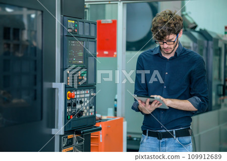 young professional engineer male  working programming automatic CNC machine in automation metal factory 109912689