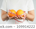 Hand holding fresh organic orange fruit and measure tape. 109914222