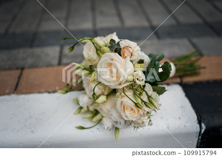 Gold wedding rings on a wedding bouquet with white flowers 109915794