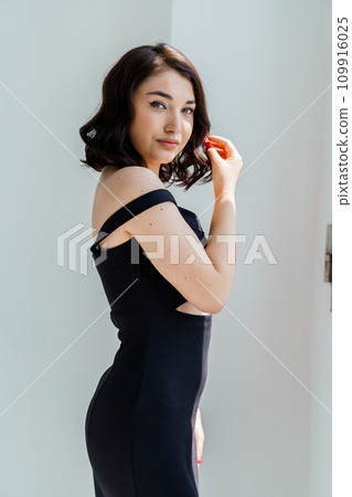 Portrait of a young beautiful girl in a black dress on a white background 109916025