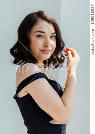 Portrait of a young beautiful girl in a black dress on a white background 109916027