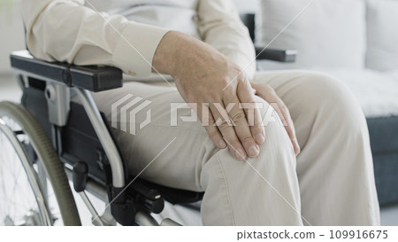 Close-up of man in wheelchair rubbing injured knee, rehabilitation after injury, arthritis Close-up of man in wheelchair rubbing injured knee, rehabilitation after injury, arthritis 109916675