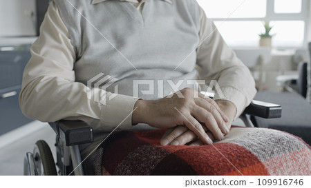 Man with  disability sitting in wheelchair, holding hands on knees, rehabilitation 109916746