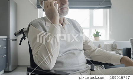 Smiling man with disability talking to family on phone, rehabilitation center Smiling man with disability talking to family on phone, rehabilitation center 109916757