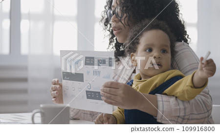 Working mom having online video call on laptop while holding baby on lap, unpaid maternity leave 109916800