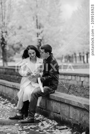 A pregnant woman sits on her husband's lap and holds small baby socks in her hands. A pregnant woman sits on her husband's lap and holds small baby socks in her hands. 109916928