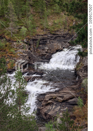 Orkla River cascades through rugged granite cliffs, bordered by dense forests in serene Stoa, Norway Orkla River cascades through rugged granite cliffs, bordered by dense forests in serene Stoa, Norway 109917007