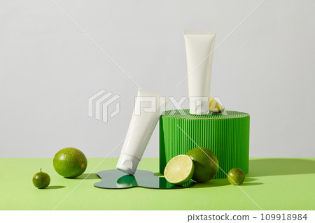Two tubes of cosmetics are displayed with a green platform, fresh lemon and acrylic sheet on the table. The essential oils in lemon help the necessary vitamins easily penetrate the epidermis. Two tubes of cosmetics are displayed with a green platform, fresh lemon and acrylic sheet on the table. The essential oils in lemon help the necessary vitamins easily penetrate the epidermis. 109918984