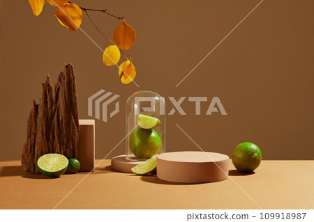 Fresh lemon and pink podium on brown background with autumn leaves and props. Lemon is an inexpensive natural cosmetic but is highly effective in exfoliating skin and treating acne. 109918987