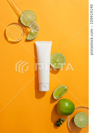 An unlabeled tube of facial cleanser is placed on a dark yellow background with fresh lemon. Vitamin C in lemon helps restore damaged skin very quickly. An unlabeled tube of facial cleanser is placed on a dark yellow background with fresh lemon. Vitamin C in lemon helps restore damaged skin very quickly. 109919140