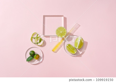 Glass platform, a petri dish, a test tube, fresh lemons and kumquats stand out on a light pink background. Space for displaying natural cosmetics with lemon extract. 109919150