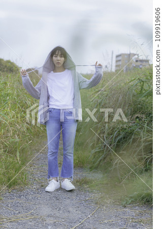 穿著連帽衫的年輕女子站在岸邊的小路上,垂直位置 穿著連帽衫的年輕女子站在岸邊的小路上,垂直位置 109919606