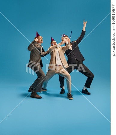 Emotional young people, men in elegant suit celebrating, having fun against blue background. Happy birthday Emotional young people, men in elegant suit celebrating, having fun against blue background. Happy birthday 109919677