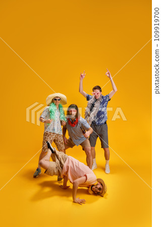 Summer trip. Cheerful young people, men having fun, drinking, dancing and laughing against yellow background 109919700