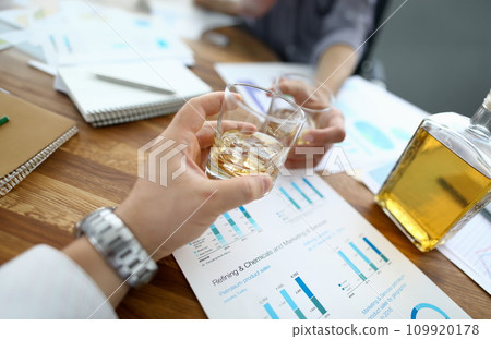 Two business people hold glass with whisky against 109920178