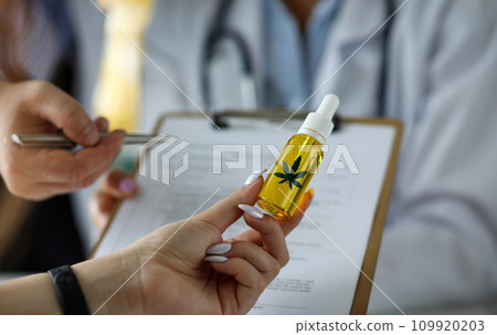 Visitor hand holding jar of cannabis concentrate oil 109920203