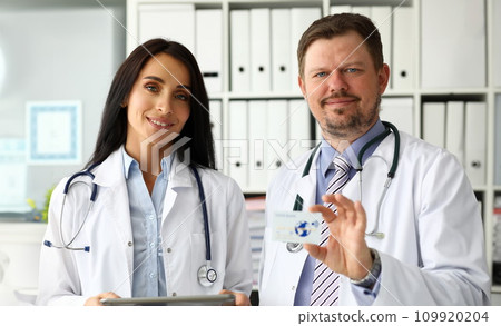 Group of smiling mature caucasian doctors offering special plastic card 109920204