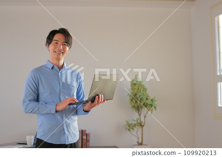 Engineer 1 smiling and standing in the office with a laptop 109920213