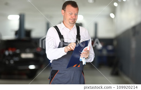 Surprised car service worker is holding a blue clipboard 109920214
