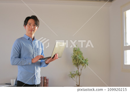 工程師 2 微笑著站在辦公室裡，手裡拿著筆記型電腦 109920215