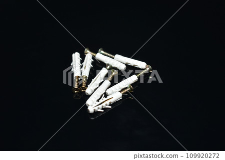 Construction dowels with plastic on a dark background. 109920272