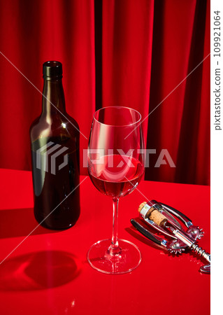 Freshly opened corkscrew bottle poured into classic tall glass of red wine served on red bar in luxury restaurant. Concept of alcohol drinks. 109921064