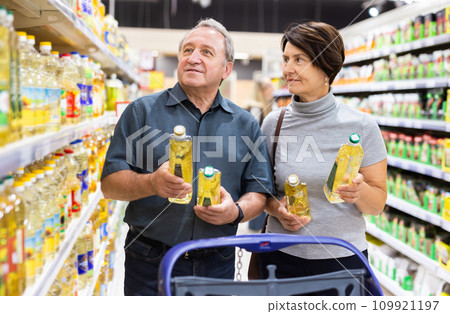 Elderly man and a woman choose extra virgin olive oil 109921197