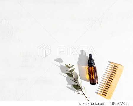 Essential oil for hair care with wooden hair comb on white background Essential oil for hair care with wooden hair comb on white background 109922093