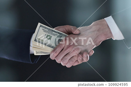 Handshake with the transfer of money on a black background 109924595