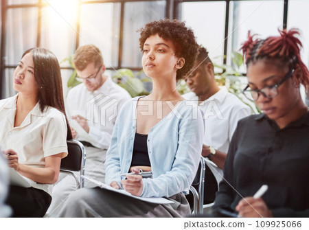 Interested happy young multiracial colleagues sitting on chairs, listening to male boss team leader Interested happy young multiracial colleagues sitting on chairs, listening to male boss team leader 109925066