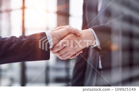 executives shaking hands in front of their manager and a colleague executives shaking hands in front of their manager and a colleague 109925149