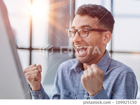 Excited modern businessman sitting at office desk and rejoicing his success Excited modern businessman sitting at office desk and rejoicing his success 109925150