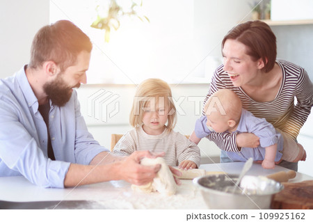 Young parents playing with children in the kitchen Young parents playing with children in the kitchen 109925162