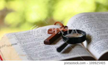 Black magnifying glass and brown wooden cross 109925405